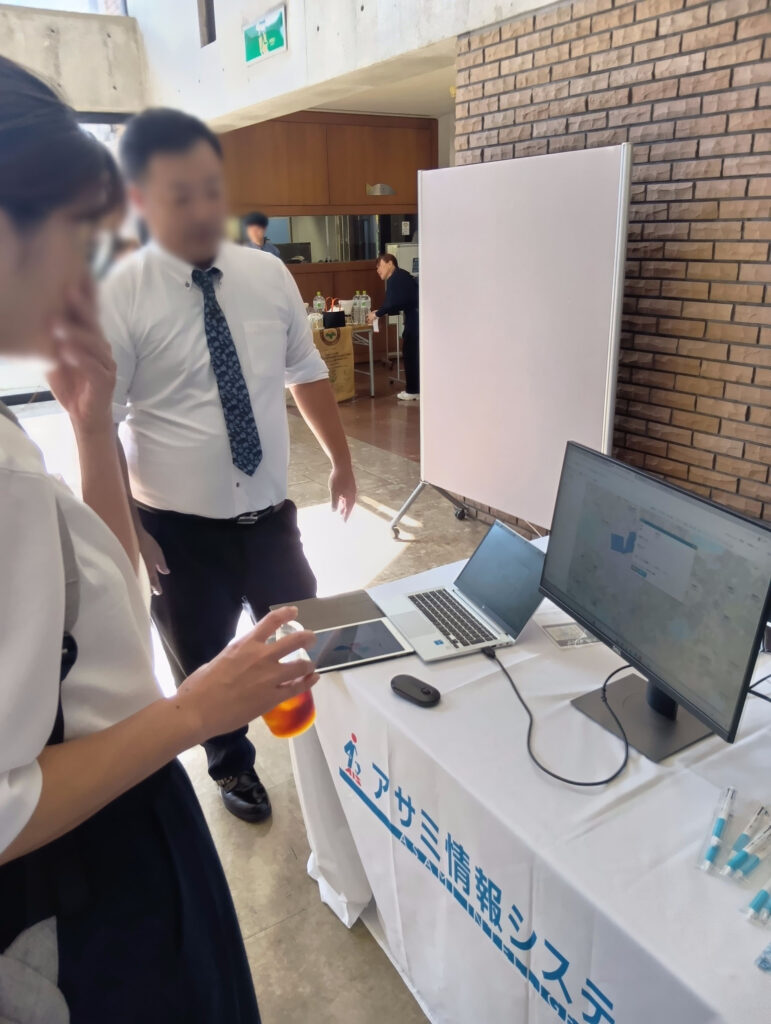 当社担当者が来場者に操作画面を見せながら当社の取り組みについて説明している。