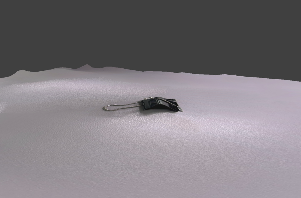 Scaniverseで約3cmのクリップをスキャンした画面。立体的に再現されず、平らな面上にクリップの画像が張り付いたようになっている様子。